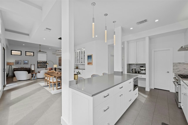 kitchen with ceiling fan, high end range, hanging light fixtures, white cabinets, and decorative backsplash