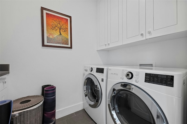 clothes washing area with cabinets, separate washer and dryer, and dark tile patterned flooring