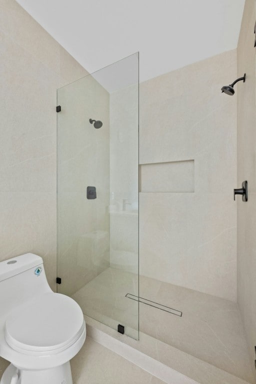 bathroom with a tile shower and toilet