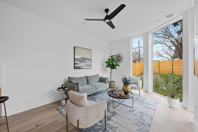 living room featuring expansive windows, ceiling fan, and light hardwood / wood-style flooring