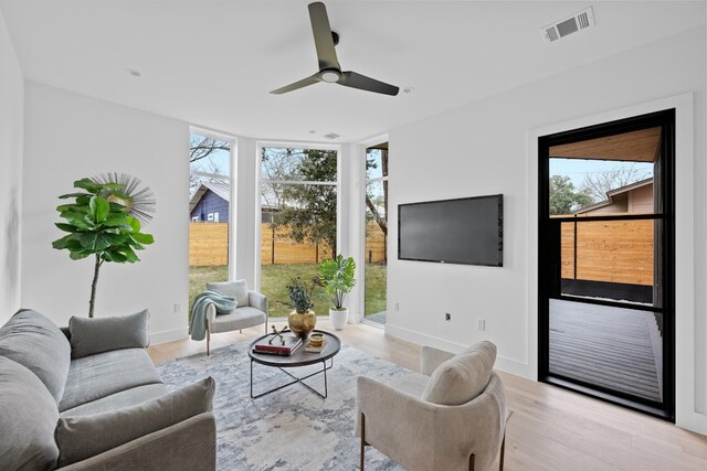 living room with floor to ceiling windows, ceiling fan, and light wood-type flooring