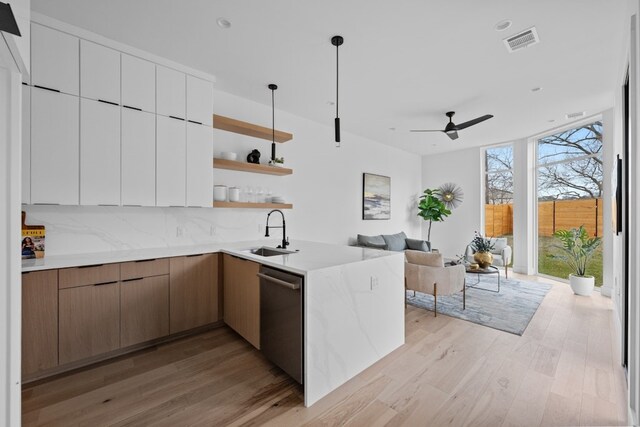 kitchen with sink, light hardwood / wood-style flooring, white cabinetry, expansive windows, and stainless steel dishwasher