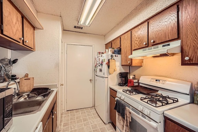 kitchen with white appliances, sink, and a textured ceiling