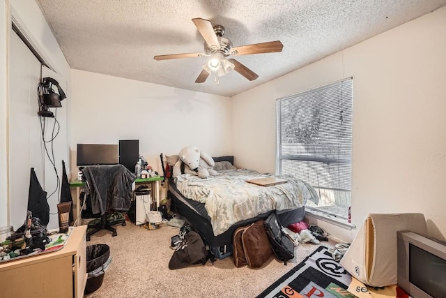 carpeted bedroom featuring ceiling fan and a textured ceiling