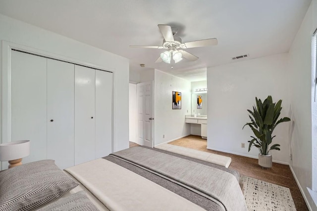 carpeted bedroom with ceiling fan, ensuite bath, and a closet