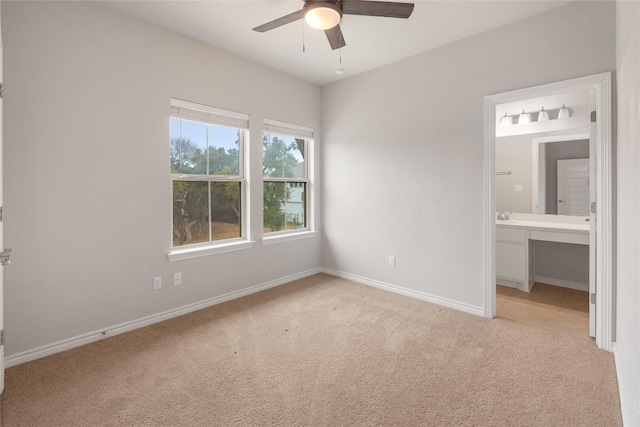 unfurnished bedroom featuring ceiling fan, sink, light carpet, and ensuite bath