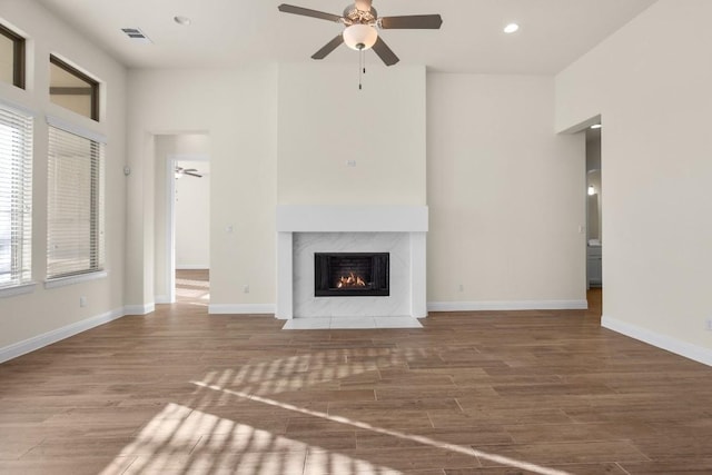 unfurnished living room featuring ceiling fan, a high end fireplace, and hardwood / wood-style floors