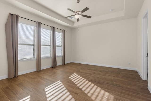 unfurnished room featuring wood-type flooring, a raised ceiling, and ceiling fan