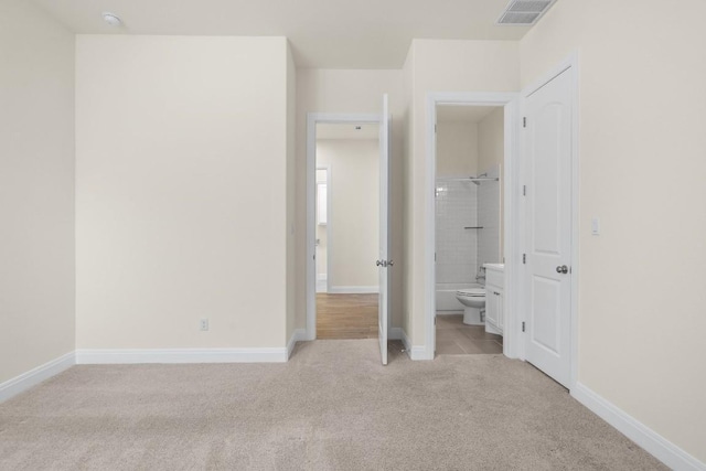 unfurnished bedroom featuring light colored carpet and ensuite bathroom