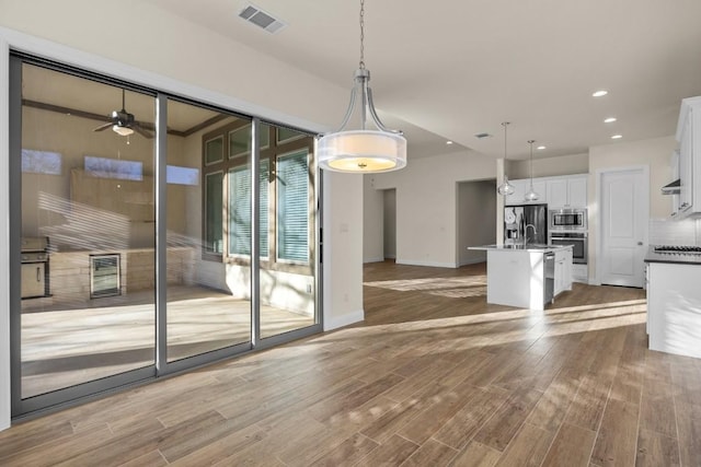 unfurnished dining area featuring hardwood / wood-style flooring, sink, and ceiling fan