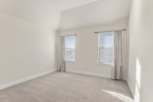 carpeted empty room featuring vaulted ceiling