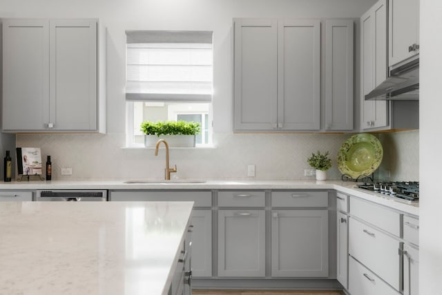 kitchen with appliances with stainless steel finishes, gray cabinets, sink, and decorative backsplash