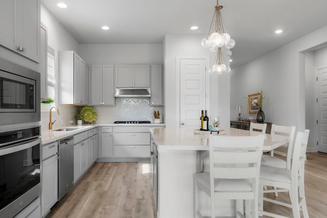 kitchen featuring sink, decorative light fixtures, a kitchen breakfast bar, a kitchen island, and stainless steel appliances