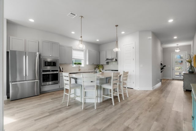 kitchen featuring stainless steel appliances, a center island, a breakfast bar area, and light hardwood / wood-style flooring