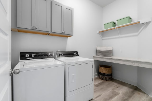 washroom with cabinets, washing machine and clothes dryer, and light hardwood / wood-style floors