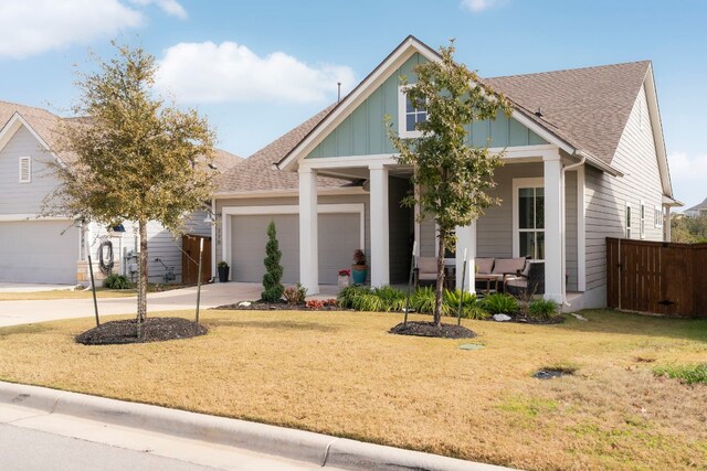 craftsman inspired home featuring a garage, a front yard, and covered porch