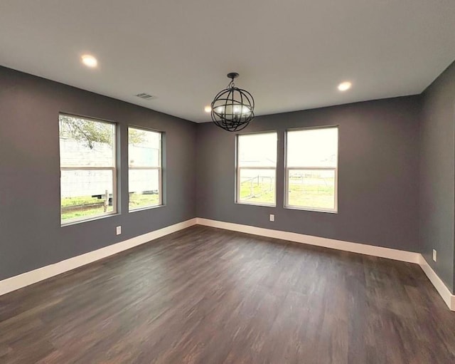 spare room with an inviting chandelier and dark hardwood / wood-style flooring