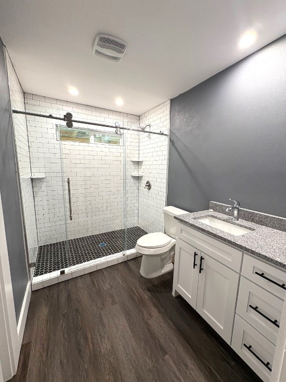 bathroom featuring vanity, wood-type flooring, toilet, and a shower with shower door