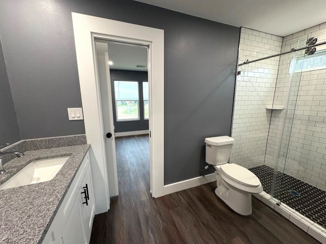 bathroom featuring wood-type flooring, toilet, a shower with shower door, and vanity