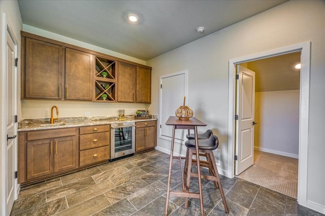 bar featuring light stone countertops, sink, and wine cooler