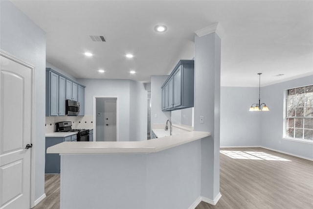 kitchen with pendant lighting, range with gas cooktop, kitchen peninsula, and light wood-type flooring