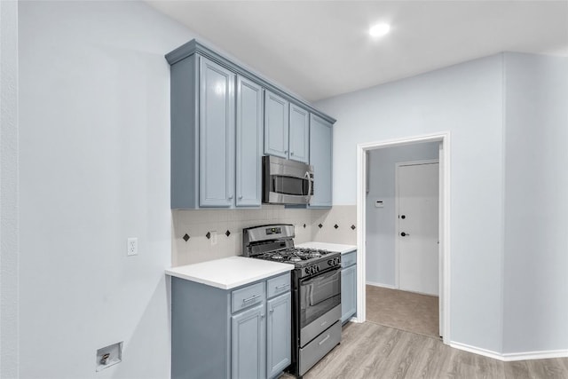 kitchen with tasteful backsplash, gray cabinetry, stainless steel appliances, and light wood-type flooring