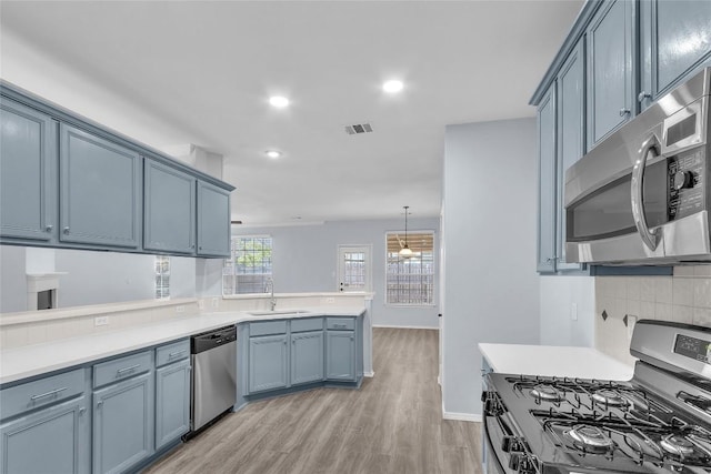 kitchen with sink, appliances with stainless steel finishes, backsplash, decorative light fixtures, and kitchen peninsula