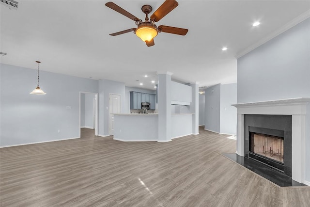 unfurnished living room featuring dark wood-type flooring, ceiling fan, and crown molding