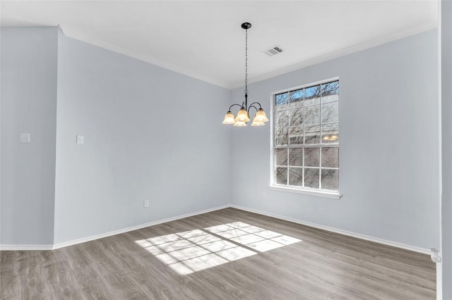 spare room featuring hardwood / wood-style flooring and a chandelier