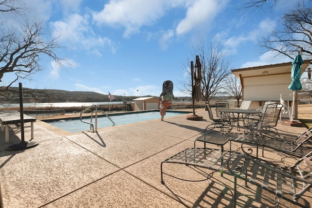 view of pool featuring a storage unit and a patio area