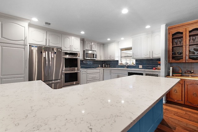 kitchen featuring dark hardwood / wood-style flooring, decorative backsplash, stainless steel appliances, and white cabinets