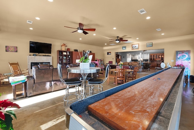 playroom with ceiling fan, a fireplace, and concrete floors