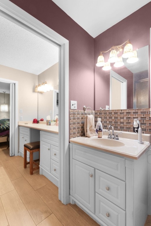 bathroom with vanity, hardwood / wood-style floors, decorative backsplash, and a textured ceiling