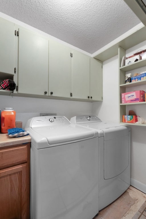 washroom with cabinets, washing machine and clothes dryer, and a textured ceiling