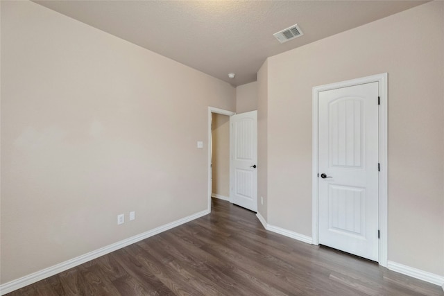 unfurnished bedroom with dark wood-type flooring and a textured ceiling