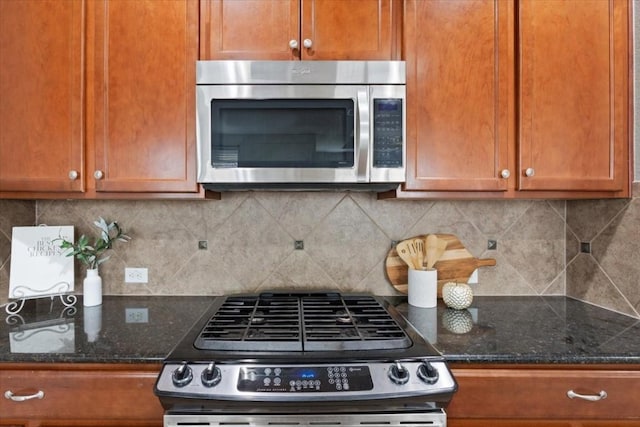 kitchen featuring stainless steel appliances, decorative backsplash, and dark stone counters