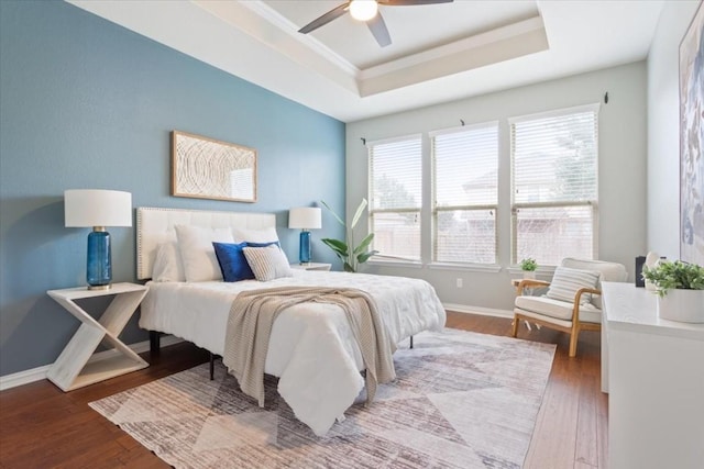 bedroom featuring crown molding, a tray ceiling, wood-type flooring, and ceiling fan