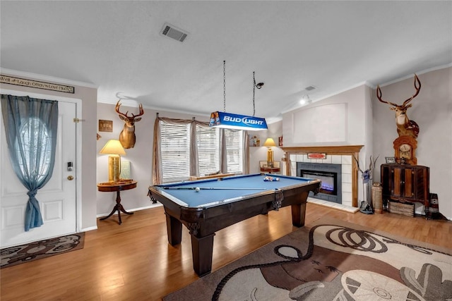 playroom featuring crown molding, pool table, vaulted ceiling, light wood-type flooring, and a tiled fireplace