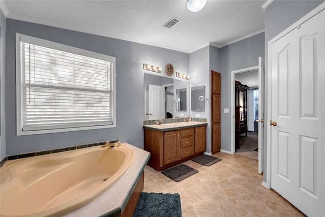 bathroom featuring vanity, ornamental molding, a textured ceiling, and a bathtub