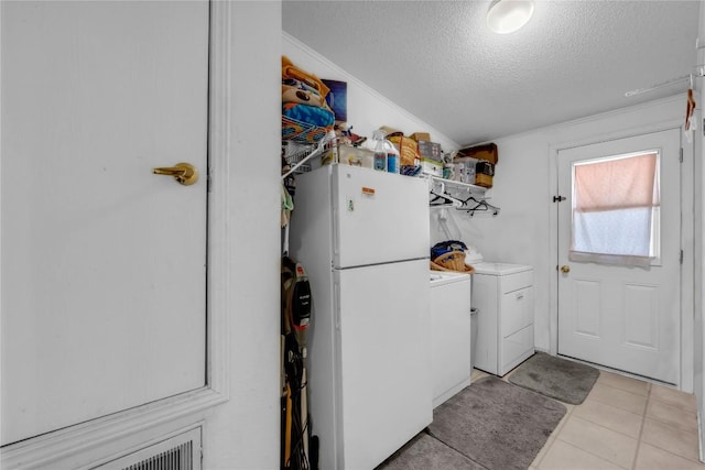 laundry area featuring crown molding, washer and clothes dryer, a textured ceiling, and light tile patterned floors