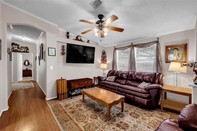 living room featuring lofted ceiling, hardwood / wood-style flooring, ornamental molding, and ceiling fan