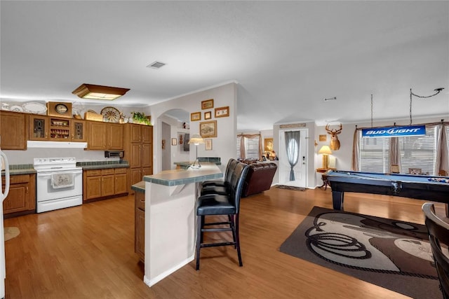 kitchen with electric stove, pool table, a breakfast bar area, and light hardwood / wood-style flooring