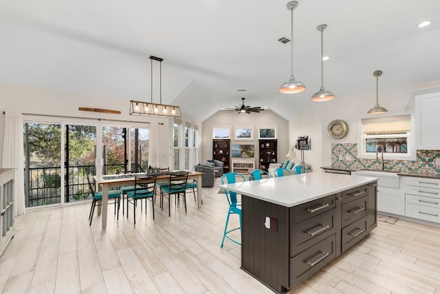 kitchen featuring hanging light fixtures, sink, white cabinets, and a kitchen bar