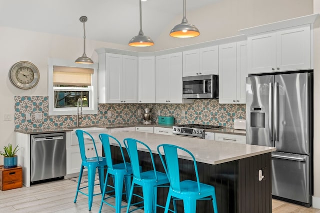 kitchen featuring pendant lighting, appliances with stainless steel finishes, white cabinetry, a kitchen island, and decorative backsplash