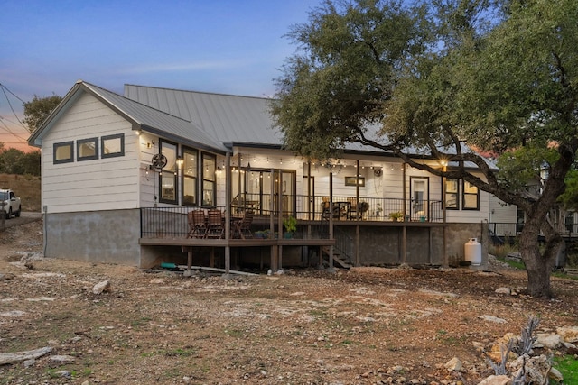 back house at dusk featuring a wooden deck