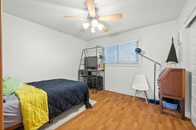 bedroom featuring light wood finished floors, a ceiling fan, and baseboards