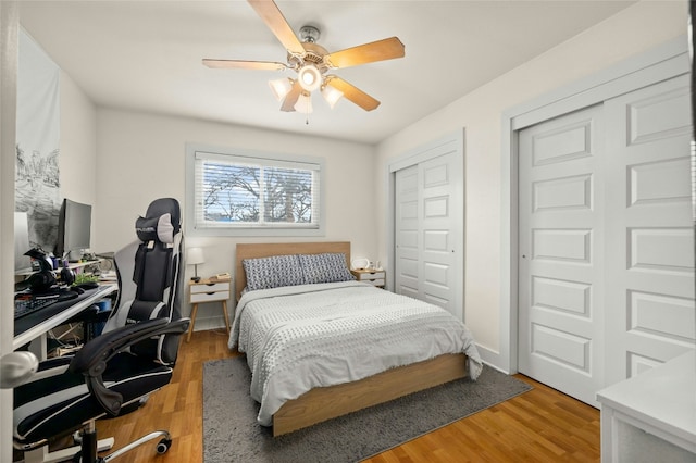 bedroom featuring ceiling fan, hardwood / wood-style floors, and two closets