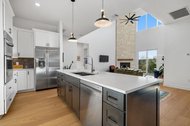 7224 Getaway Dr, Jonestown, TX 78645 - kitchen featuring appliances with stainless steel finishes, a sink, a ceiling fan, a stone fireplace, and white cabinets