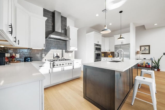 7224 Getaway Dr, Jonestown, TX 78645 - kitchen featuring wall chimney range hood, appliances with stainless steel finishes, light wood-type flooring, a sink, and tasteful backsplash