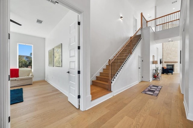 interior space with hardwood / wood-style flooring, a fireplace, and a towering ceiling